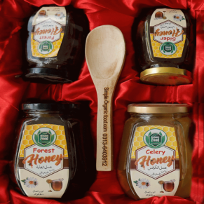 Four jars of honey in a red box with a wooden spoon